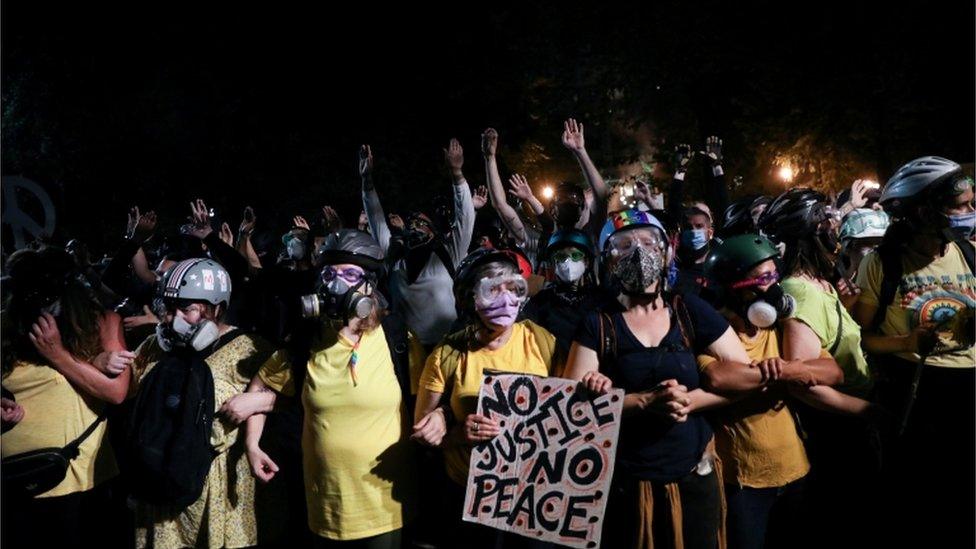 A group of mothers stands between protesters and federal officers in Portland