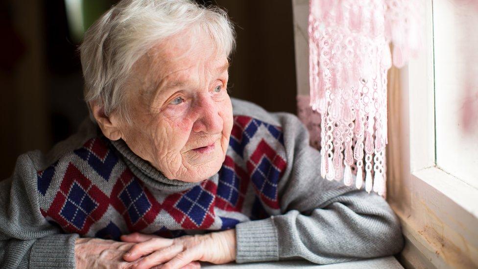 Elderly man gazing out the window