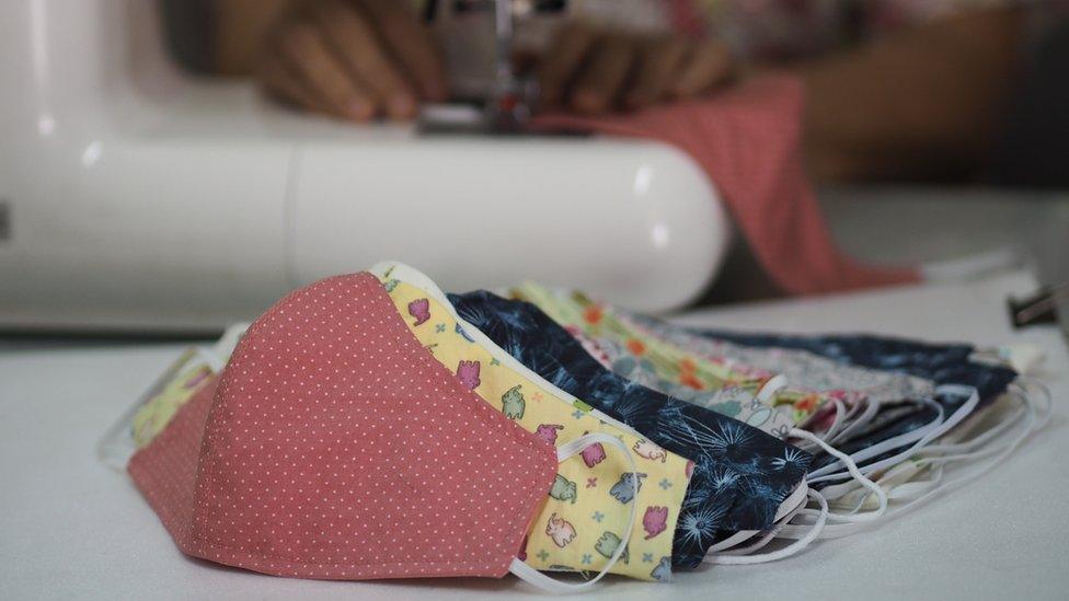 Homemade cloth masks in front of a person using a sewing machine