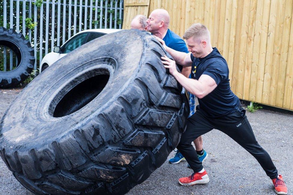 People trying to flip a tyre