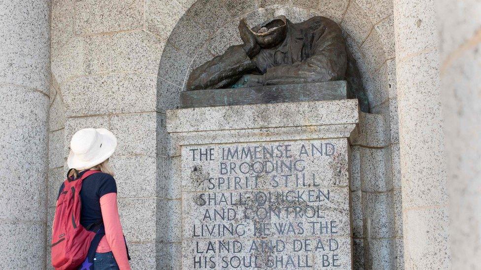 Visitor looks at damaged Rhodes statue