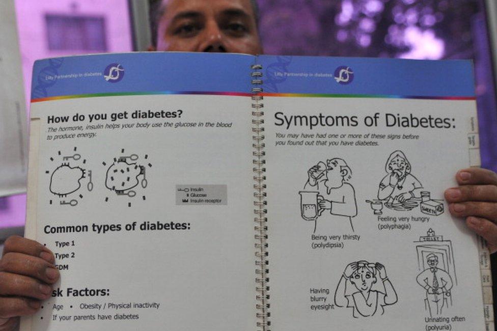 A medical assistant holds up a booklet with information on diabetes at a private clinic in New Delhi on November 8, 2011