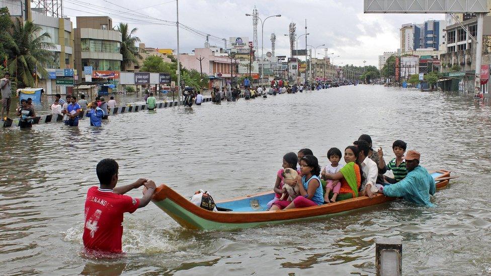 People travel on a boat as they move to safer places through a flooded road in Chennai