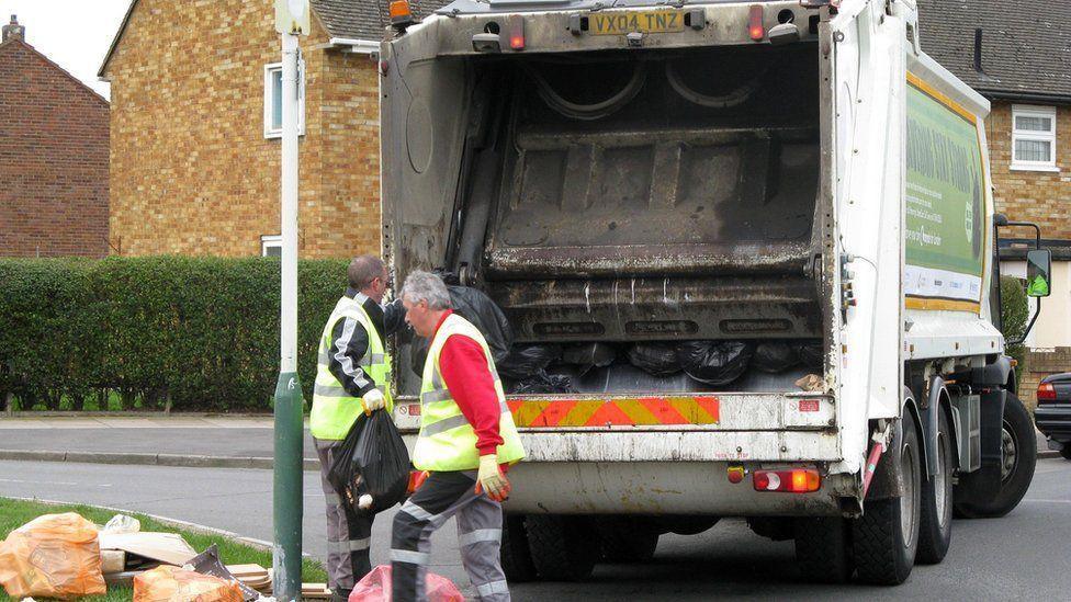 Two refuse collectors standing by a bin lorry