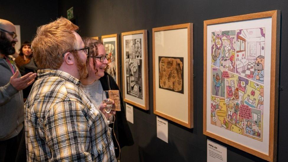 People looking at artwork inspired by the hotel toilets