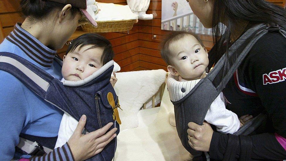 Two mothers carry their babies at a Pregnancy and Maternity exhibition