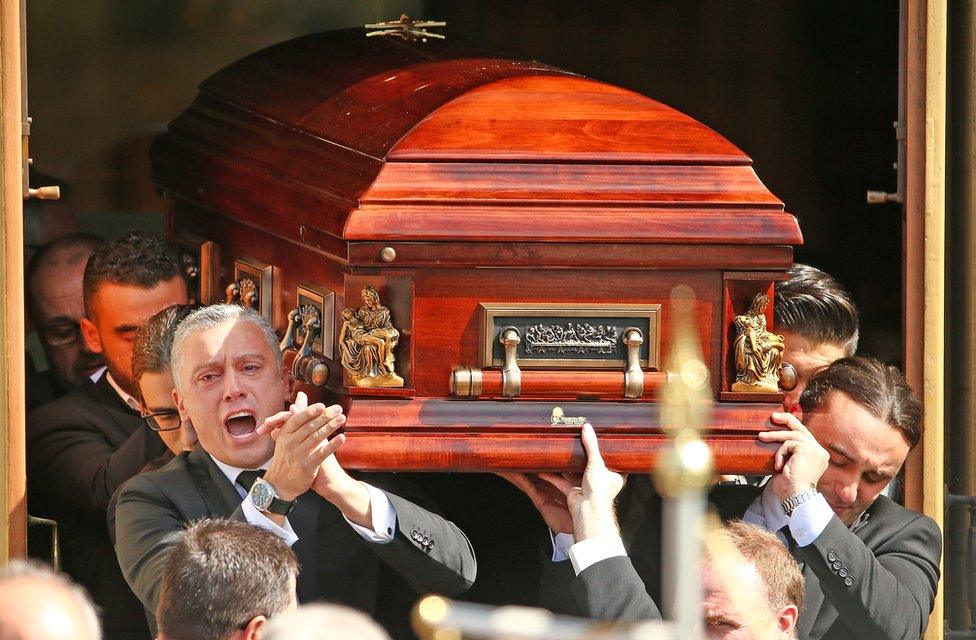 Joseph "Pino" Acquaro's brother Massimo applauds as he and fellow pallbearers carry the coffin from St Mary's Star of Sea Catholic Church