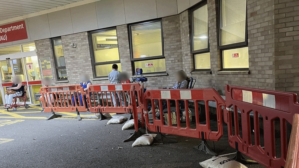 Patients sitting under blankets and a nurse outside accident and emergency at Addenbrooke's Hospital in Cambridge