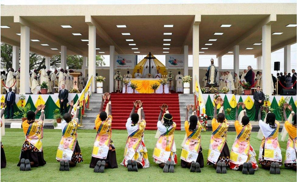 People kneeling down in front of a stage during the Mass