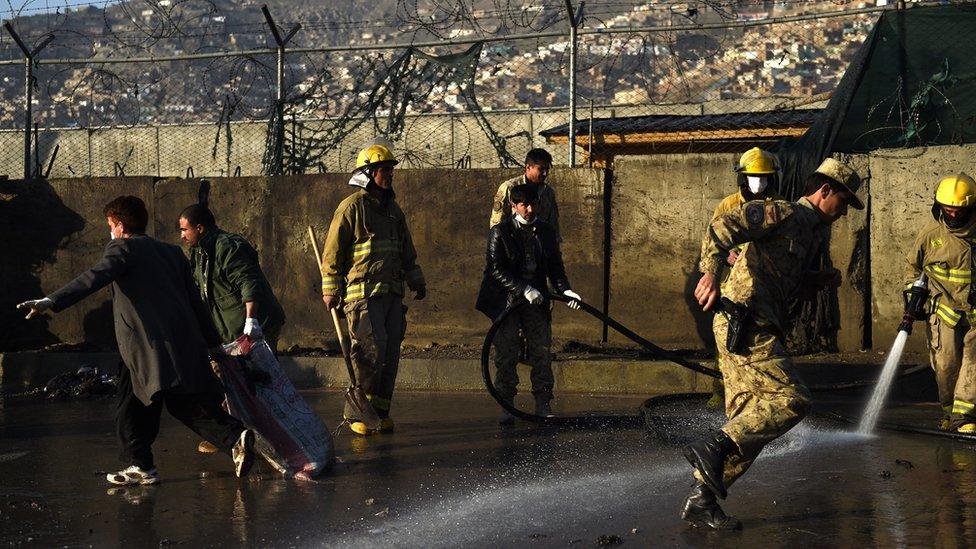 Afghan workers clear the site of a suspected Taliban suicide bombing