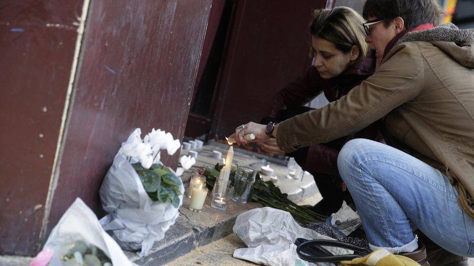 People leave flowers and light candles outside of the Carillon bar in the 10th district of Paris on November 14, 2015