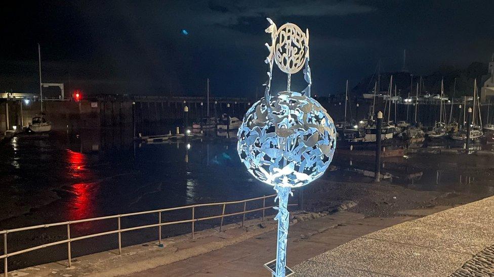 Sculpture of a dome shape with metal geese, against a night background