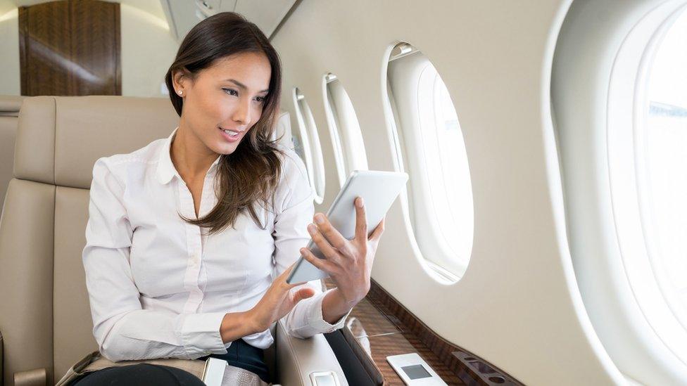 Woman on jet checking her tablet