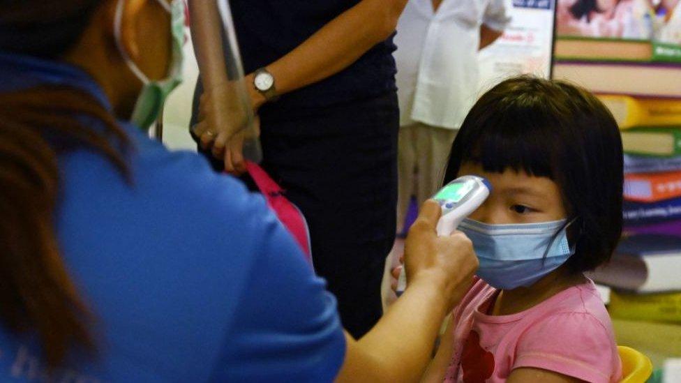 Student gets temperature taken in Singapore