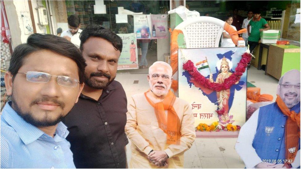 Mayank Patel celebrating and posing with the statue of Narendra Modi and Amit Shah.