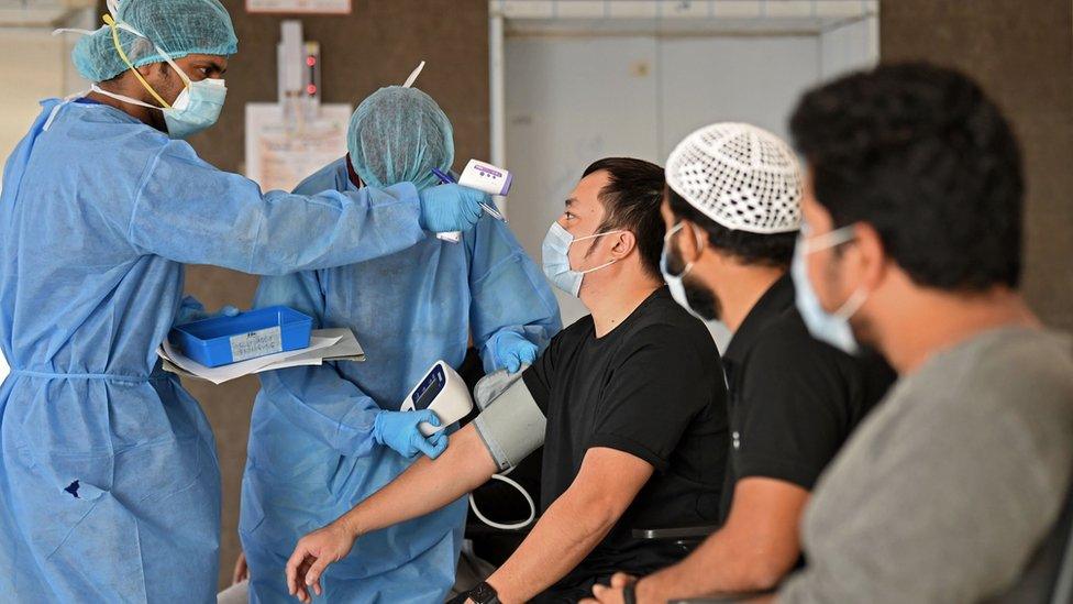 Migrant workers have their temperature and blood pressure checked by medics before leaving a medical facility in Dubai (22 April 2020)