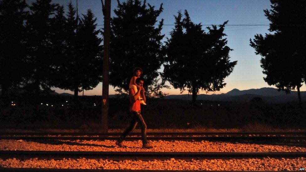 Migrants walk on the railway on the border between Greece and Macedonia near the town of Idomeni