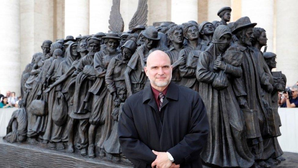 Timothy P. Schmalz stands in front of the sculpture