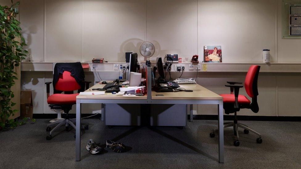 a desk with two office chairs, one side is very cluttered and the other is empty