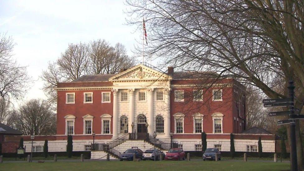 Warrington Town Hall: a Georgian building dominated by a white and brick-coloured facade, with four central columns topped by a pediment.