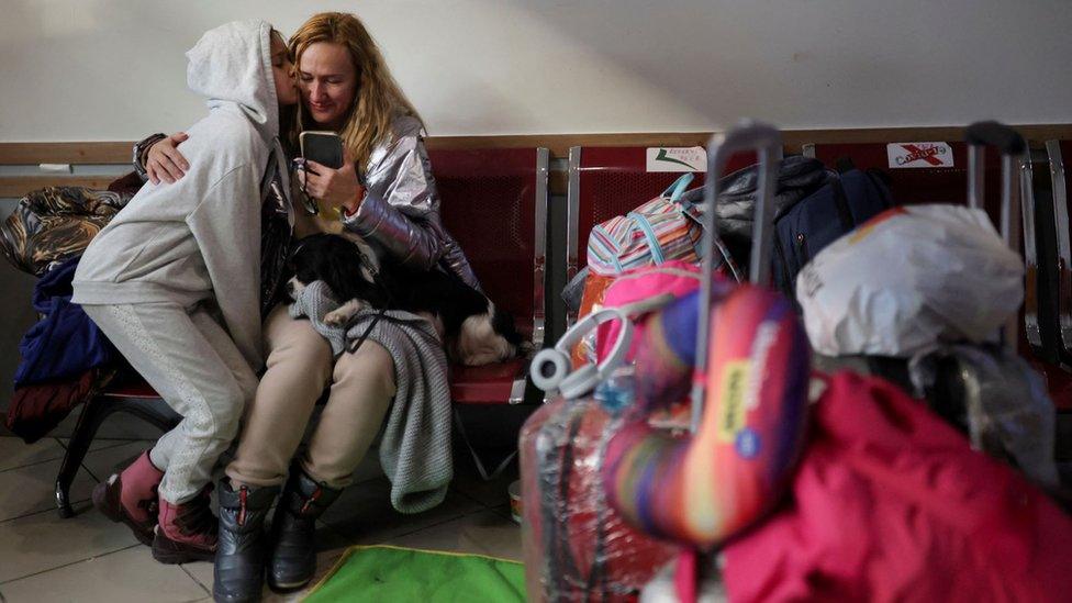 Ukrainian refugee Olena Kalynovska looks at an image of her husband after disembarking a train in Bucharest