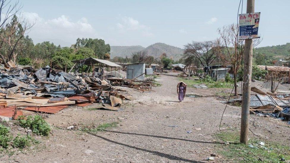 A woman walks among the remains of a destroyed factory in Ataye, Ethiopia, on May 15, 2021.