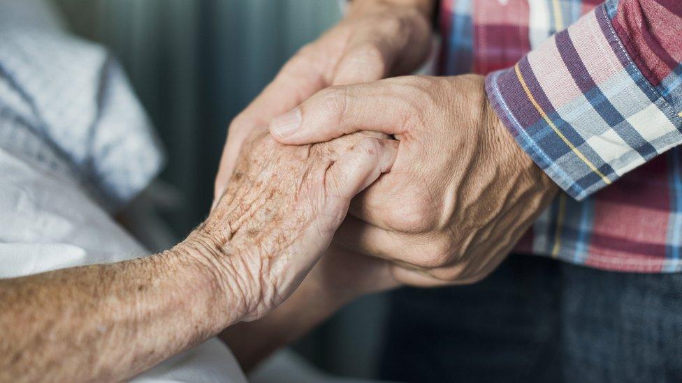 A son holding his mother's hand