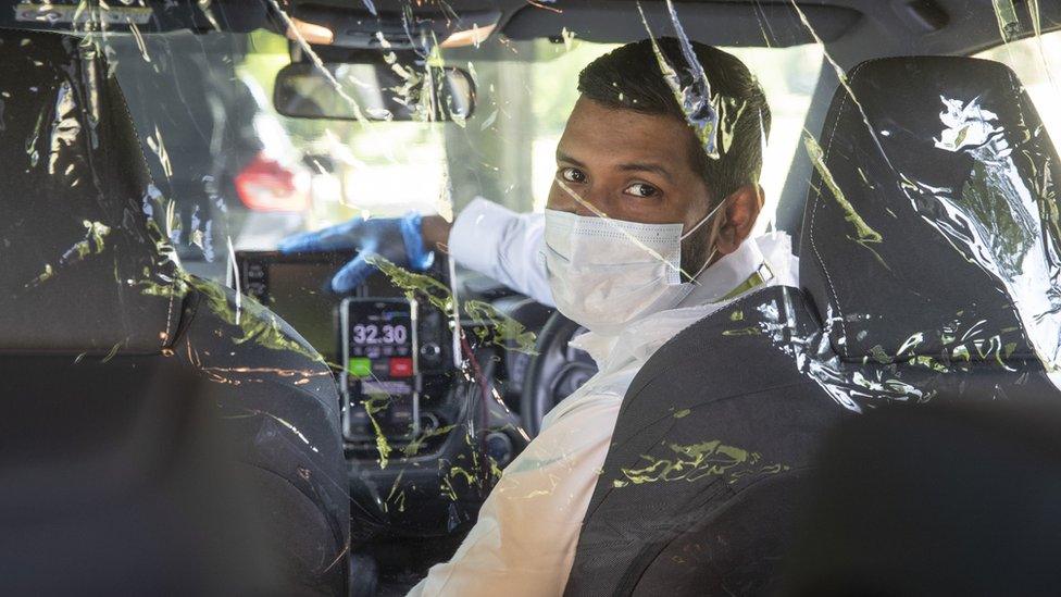 A taxi driver behind a protective coronavirus screen