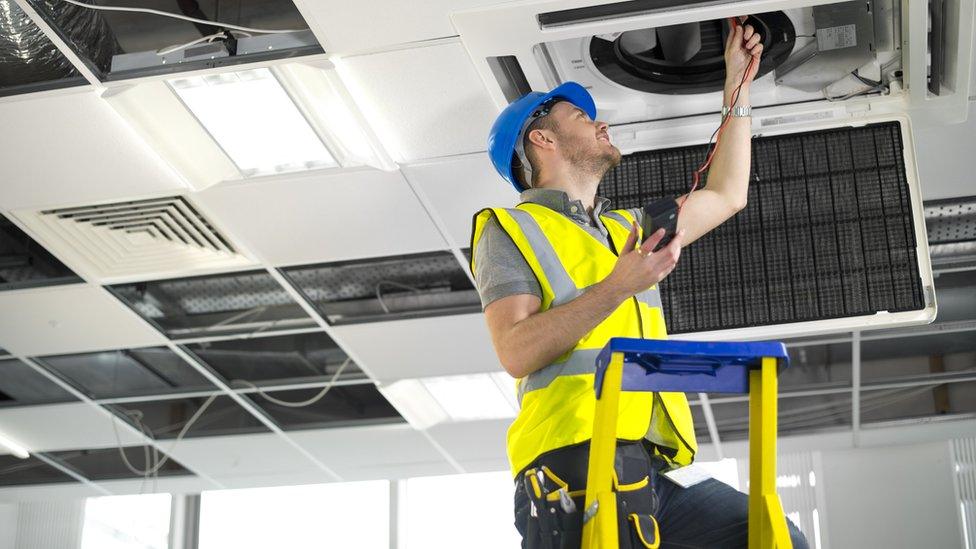 A workman fixing an air-conditioning vent