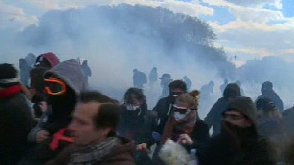 People running away from a cloud of smoke, with sunglasses and scarves over their faces, at a French protest, 28 April 2016