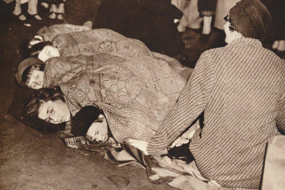 A mother watches over her children as they sleep on The Mall, to ensure their place to see the coronation of King George VI