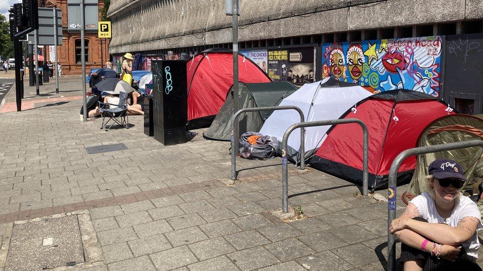 Tents lined up on Westgate Street in Cardiff, with one person sat by their tent in the bottom right corner