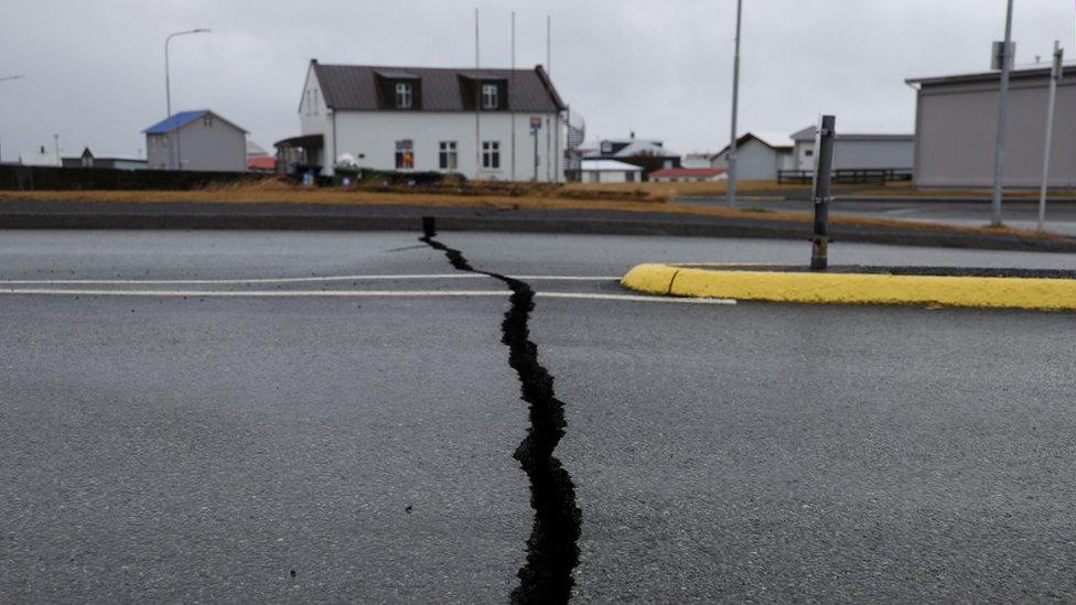 pictures shows a road with a very large crack running across it