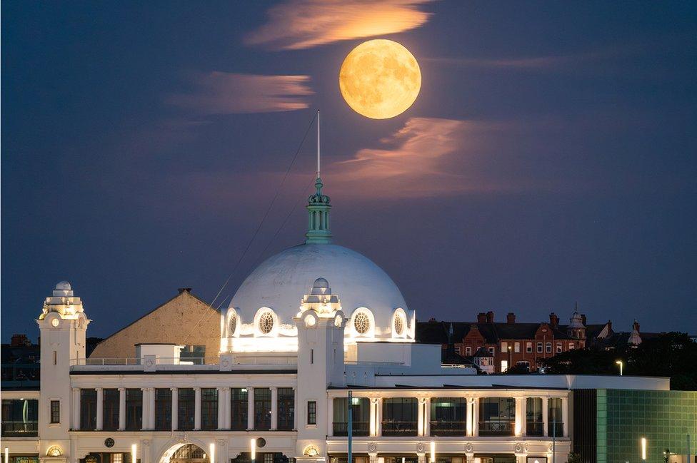 A large moon over an ornate domed building