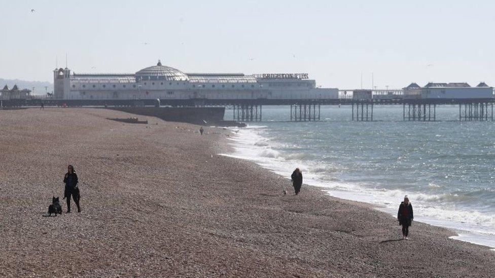 People walk along Brighton beach on Sunday 5 April