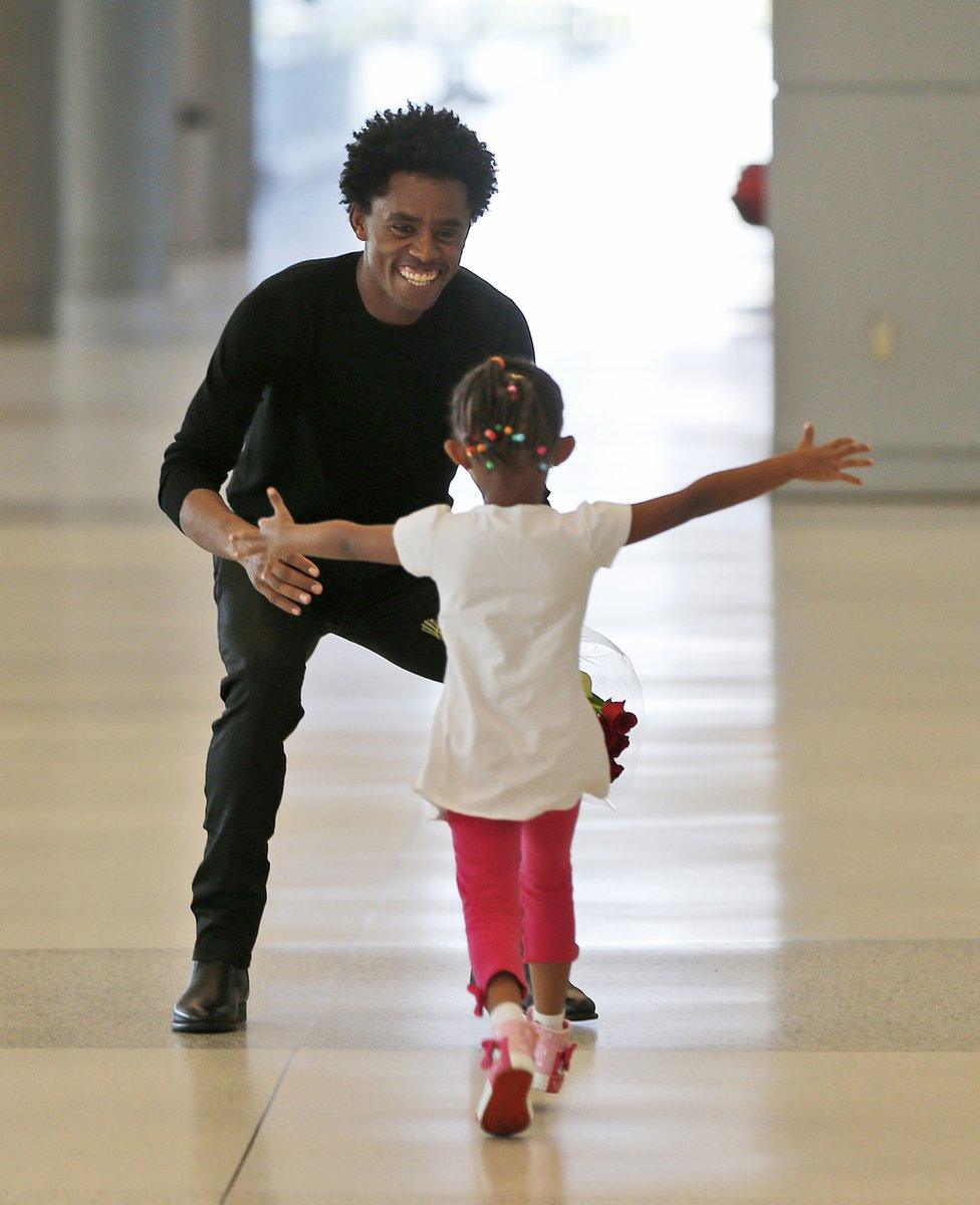 Olympic silver medallist Feyisa Lilesa, left, of Ethiopia, crouches to hug his daughter Soko, five, while picking up his family at Miami International Airport, Tuesday, 14 February 2017, in Miami.