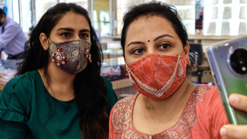 Two women wearing decorated facemasks