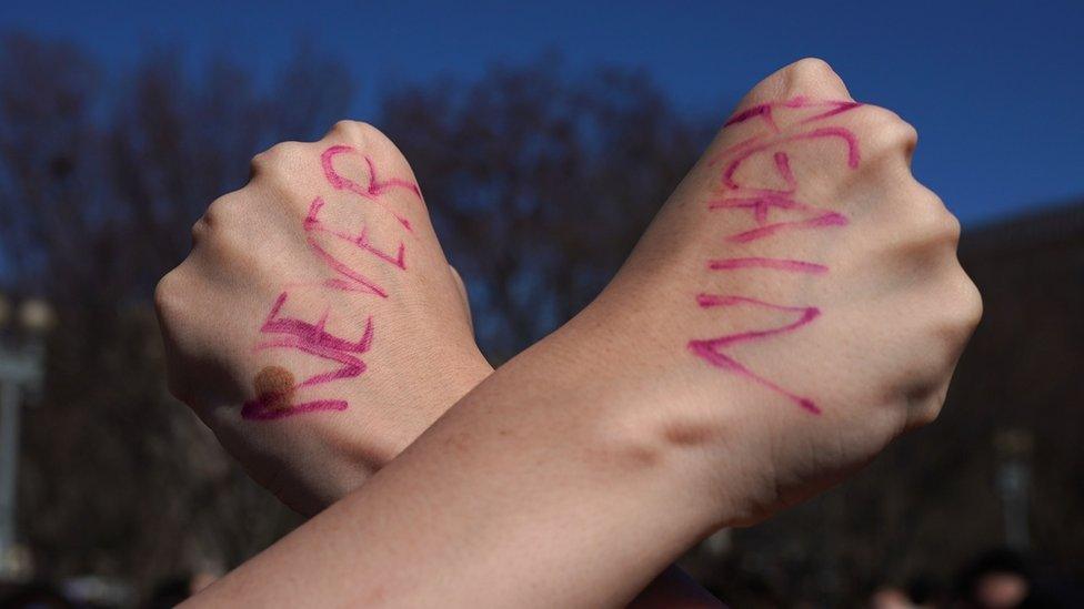 Two hands with "Never Again" written on them