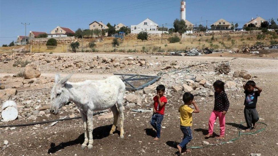 Palestinian children play near a donkey in Um al-Kheir in front of Israeli settlement of Maon (14/06/20)