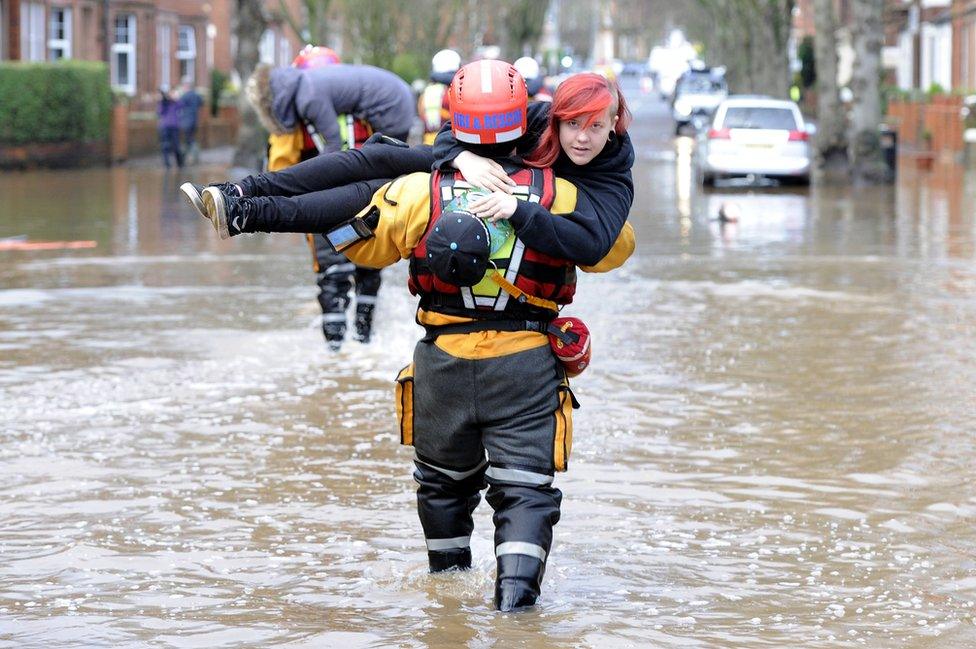 A woman is carried to safety by a rescue worker in Carlisle