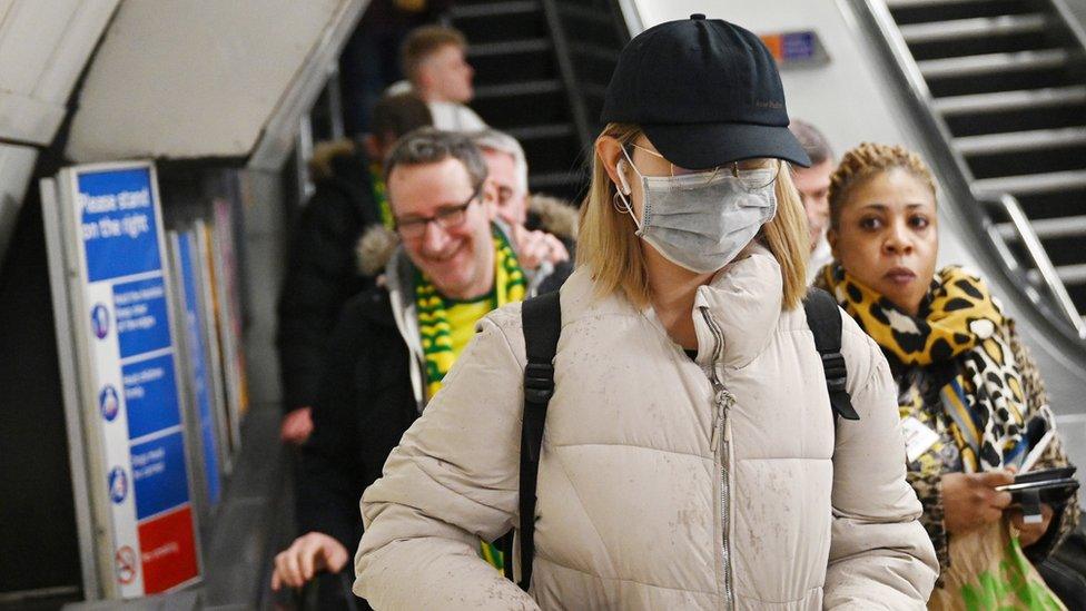 A woman wears a mask as she uses the Underground transport system in London,