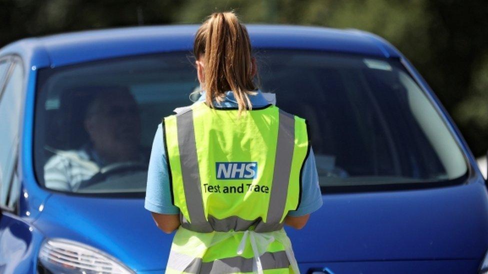 A person with an NHS test and trace jacket on