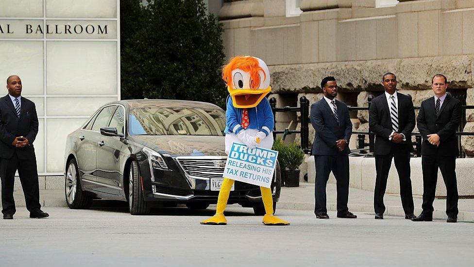 A person in a Donald Duck suit stands outside the Trump hotel in Washington, DC