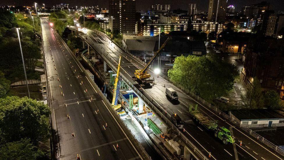 Roadworks taking place on a deserted stretch of motorway at night.