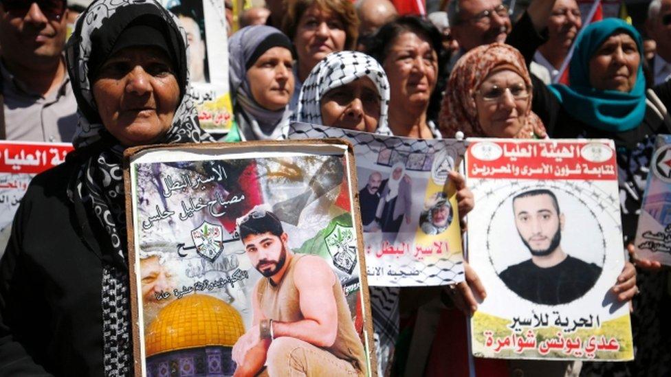 Protesters hold portraits of Palestinian prisoners during a rally in Ramallah as hundred of detainees launch a hunger strike on 17 April 2017