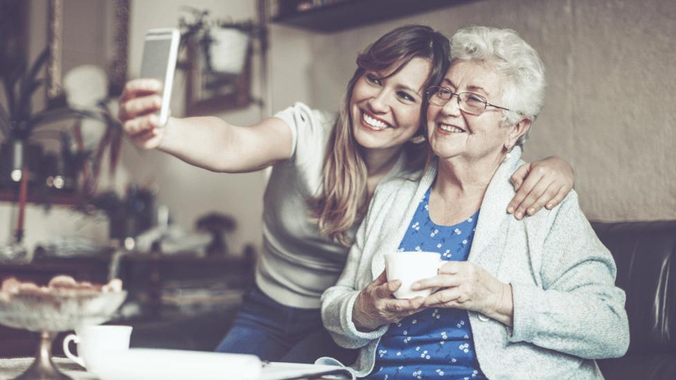 Lady taking a picture with older woman