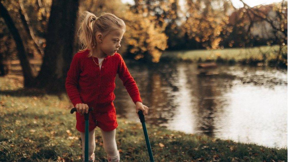 Girl with cerebral palsy going for a walk by a river with the support of mobility aids