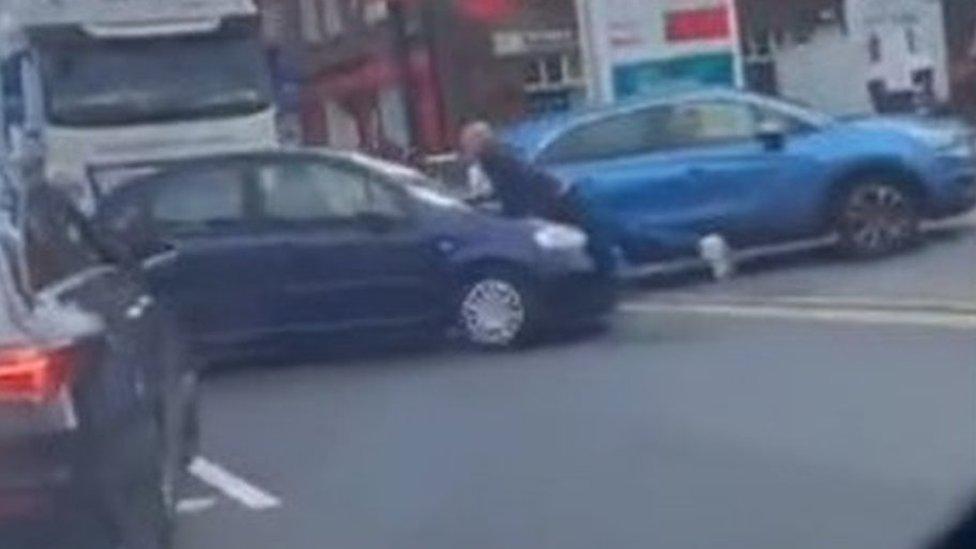 Man on bonnet of car