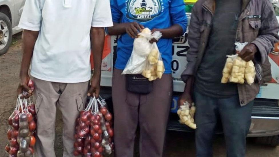 three vendors holding foodstuff in plastic bags