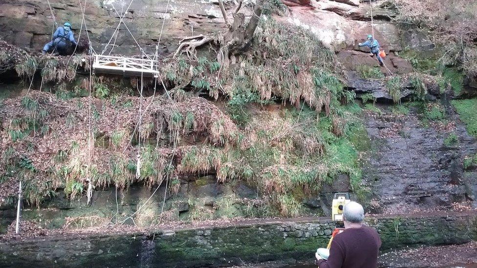 Archaeologists examining the rock face